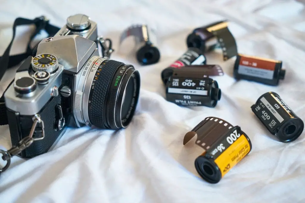 35mm film camera on bed with 35mm film canisters