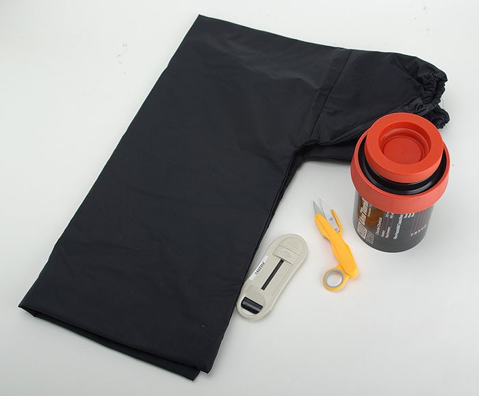 A film changing bag with a development tank, scissors, and a film canister removal tool